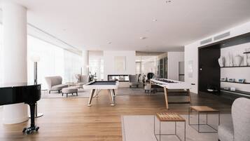A modern living room with a pool table, a piano, and a sofa.