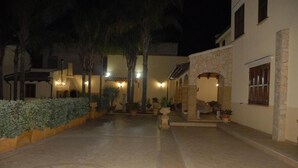 A courtyard with a central star-shaped mosaic, surrounded by potted plants and palm trees. - PRESTIGIOSA E SINGOLARE VILLA CON APPARTAMENTO CAMERE E PISCINA AD USO ESCLUSIVO (MAZARA DEL VALLO)