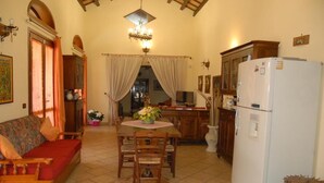 A cozy living room with a sofa, dining table, chairs, and a refrigerator. - PRESTIGIOSA E SINGOLARE VILLA CON APPARTAMENTO CAMERE E PISCINA AD USO ESCLUSIVO (MAZARA DEL VALLO)