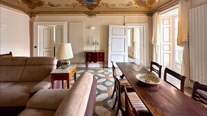 A spacious living room with a sofa, a dining table, and a patterned floor. - Cà del Conte Lake Como (Tremezzo)
