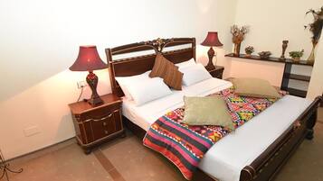 Un dormitorio con una cama de madera, dos mesitas de noche, una lámpara roja y una manta de colores.