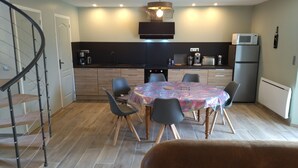 Una cocina moderna con comedor, que incluye una mesa redonda con sillas, una escalera y un microondas.