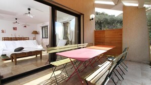 A room with a bed, a table, and chairs, a wooden fence, and a view of trees. - Villa des Oliviers (Buis-les-Baronnies)