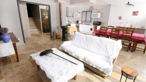 A living room with a sofa, a table, and a chair. There is a staircase leading to another room. - Villa des Oliviers (Buis-les-Baronnies)