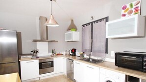 A modern kitchen with stainless steel appliances, a washing machine, and a microwave. - Villa des Oliviers (Buis-les-Baronnies)