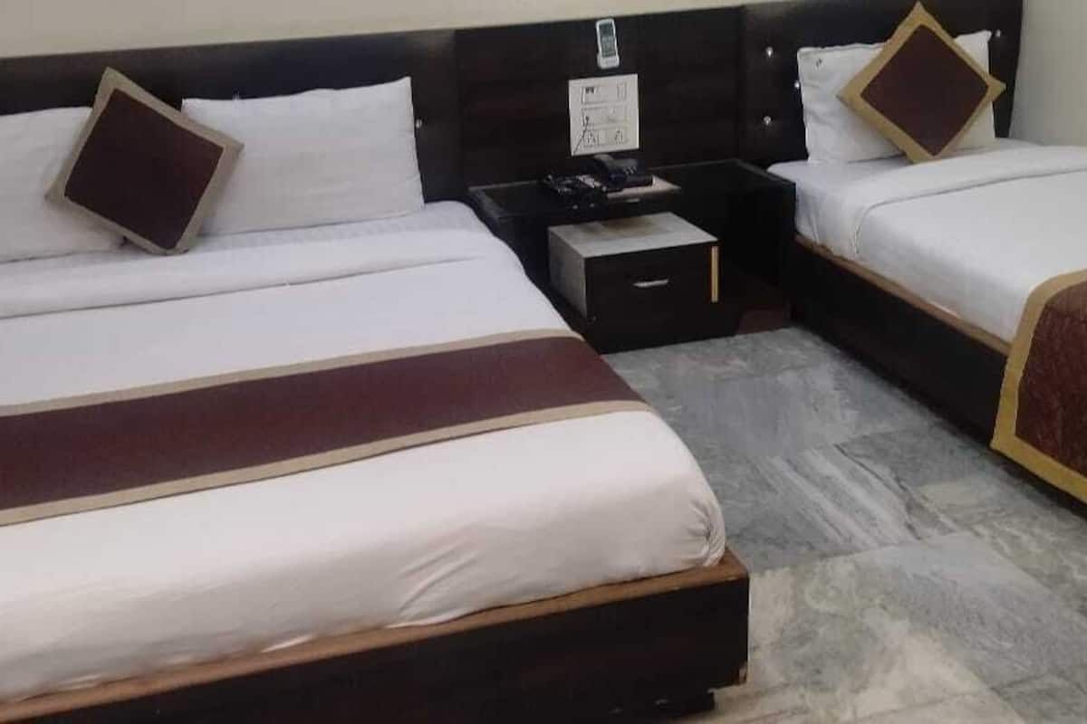Quarto de hotel com duas camas de solteiro, uma mesa de cabeceira e uma pequena mesa.