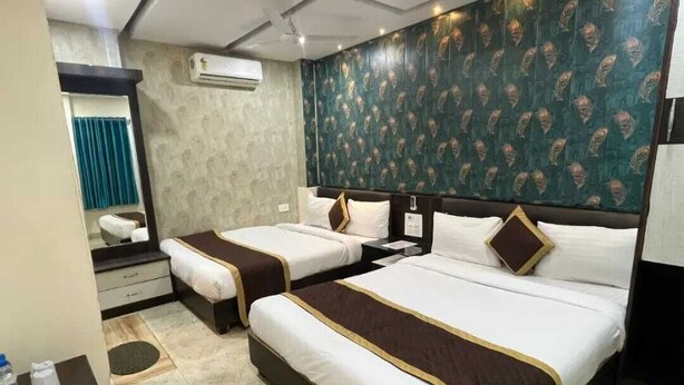 Una habitación de hotel con dos camas, un espejo, un equipo de aire acondicionado y una pared con diseño.