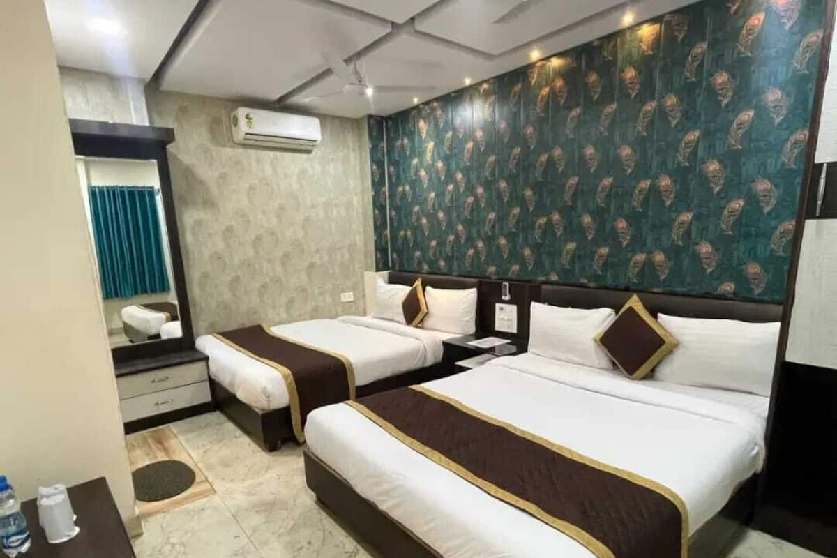 Quarto de hotel com duas camas, um espelho, aparelho de ar condicionado e parede com padrão.