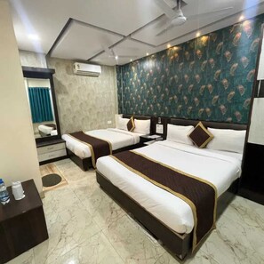 A hotel room with two beds, a mirror, an air conditioning unit, and a patterned wall. - Hotel Raj Villas (Udaipur)