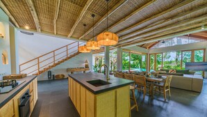 Eine geräumige Küche mit einer zentralen Kochinsel, einer Treppe und einem Essbereich mit einer Couch und Stühlen.