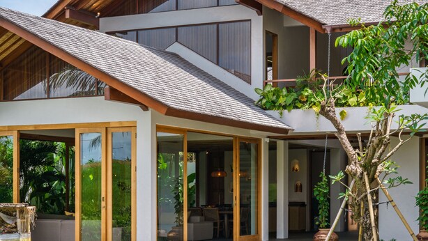 Ein modernes, zweistöckiges Haus mit Pool, großen Glasfenstern und einer Holzterrasse.