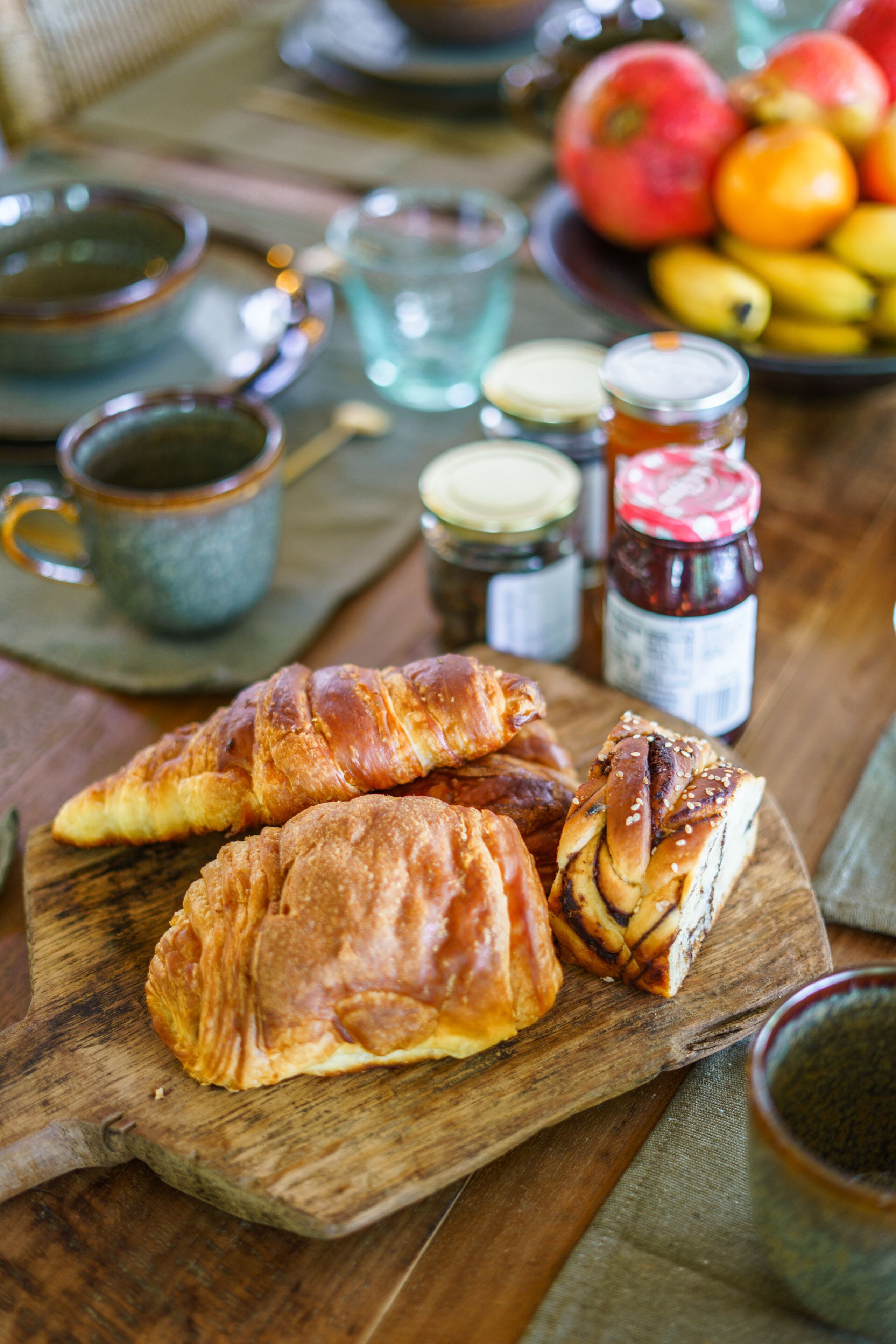 A wooden board with pastries and jars of jam.