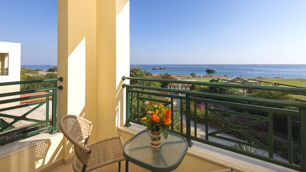 A balcony with a view of the sea, a chair, and a table with a vase of flowers. - THERETRA KIOTARI VILLAS (Rhodes)