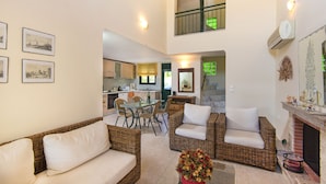 A spacious living area with wicker furniture, a dining table, and a kitchen in the background. - THERETRA KIOTARI VILLAS (Rhodes)