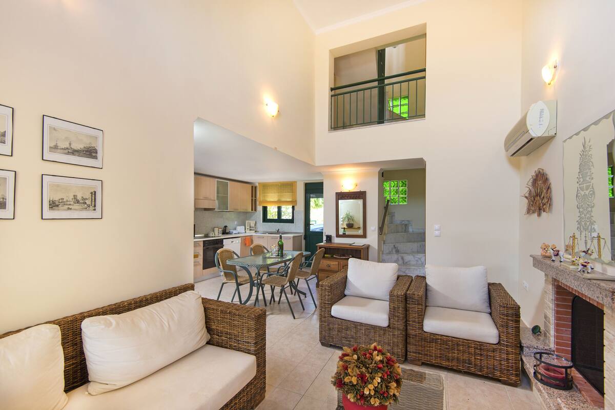A spacious living area with wicker furniture, a dining table, and a kitchen in the background.