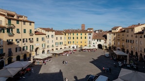 A spacious square with buildings on either side, featuring balconies and a central tower. - Guest House Bianca (Lucca)