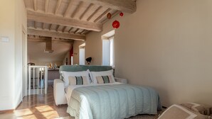 A bedroom with a bed, a window, a door, and a kitchen area in the background. - Guest House Bianca (Lucca)
