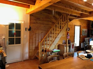 A wooden interior with a staircase, a dining table, chairs, and a kitchen area. - Barn in a green setting (Germs-sur-l'Oussouet)