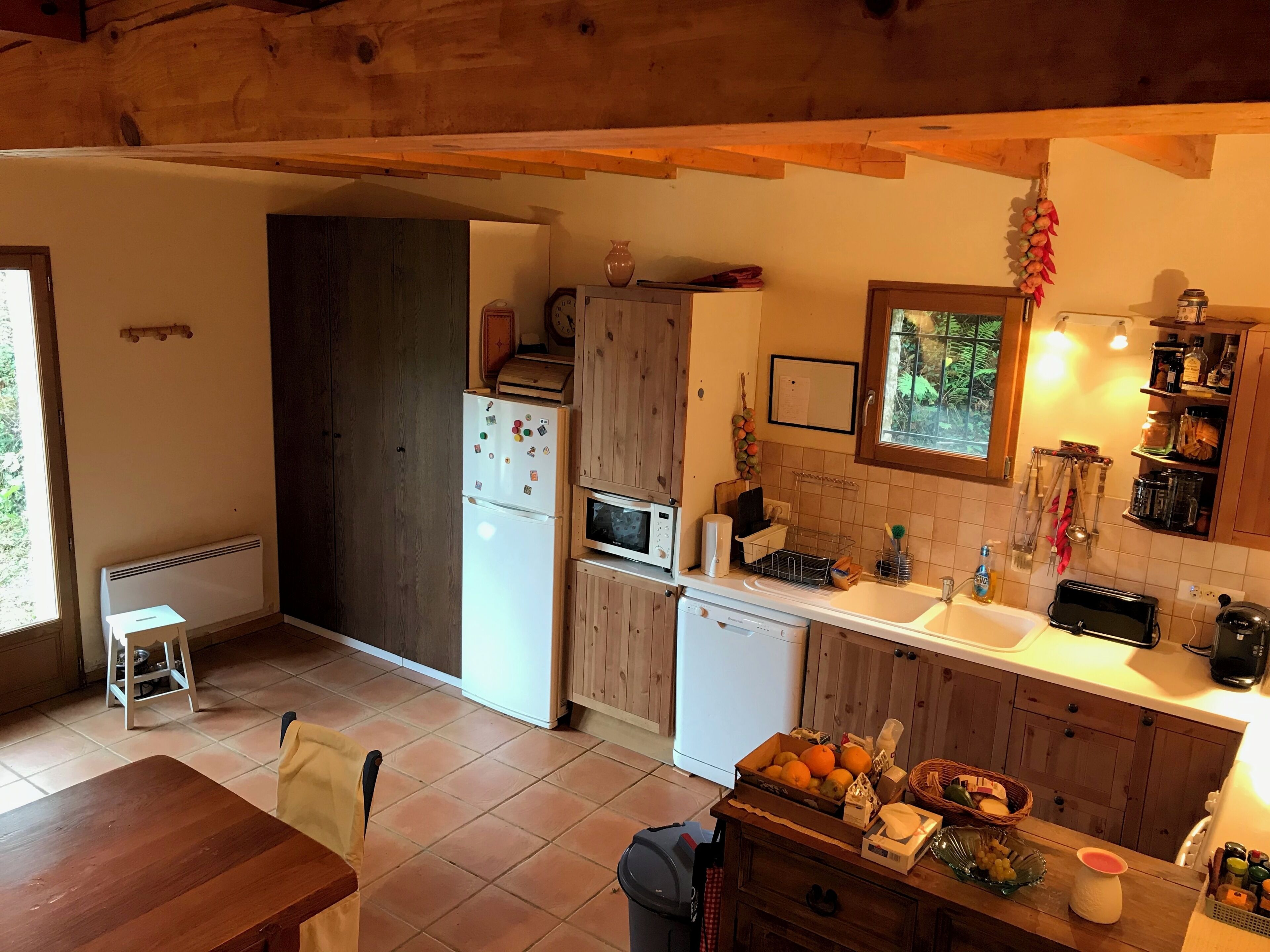 A kitchen with wooden cabinets, a refrigerator, a microwave, a sink, and a dining area with a table and chairs.