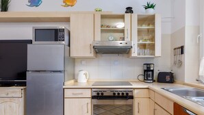 A compact kitchen with a refrigerator, microwave, stove, and sink. - Apartment with Garden close to the Beach | Private Parking (Pobierowo)