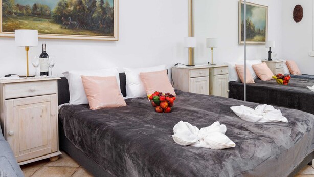 A hotel room with two beds, a large painting on the wall, a mirror, and a nightstand with a lamp and a bottle of wine. - Apartment with Garden close to the Beach | Private Parking (Pobierowo)