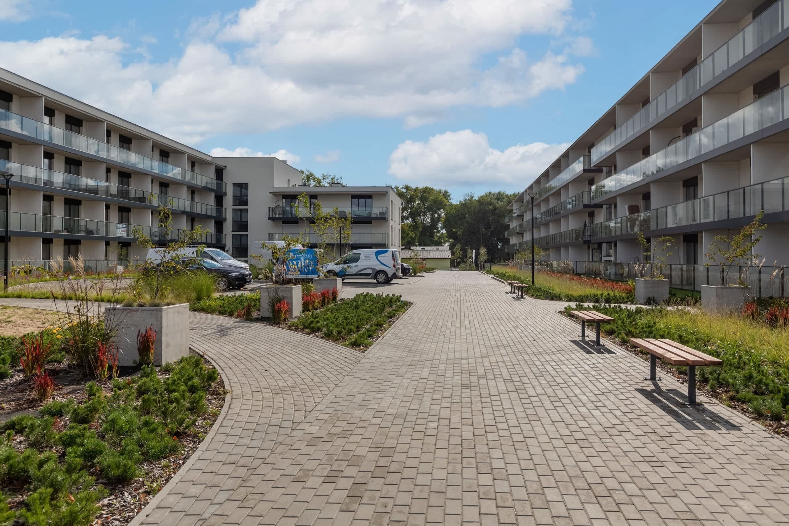 Een modern appartementencomplex met een centrale binnentuin, verharde paden en zitgedeeltes buiten.