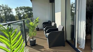Ein Balkon mit Korbmöbeln, einem Blumentopf und einer Glastür.