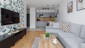 Ein modernes Wohnzimmer mit einem grauen Sofa, einem Holztisch und einem Fernseher auf einem dunklen Holzschrank.