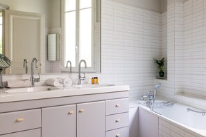 Une salle de bain moderne avec un grand lavabo, deux robinets, un miroir et une fenêtre.