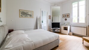 A bedroom with a bed, a dresser, a television, and a radiator. - Postcards from the Eiffel Tower, by Veeve (Paris)