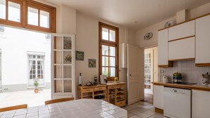 A kitchen with a dining table, cabinets, and a dishwasher. - Postcards from the Eiffel Tower, by Veeve (Paris)