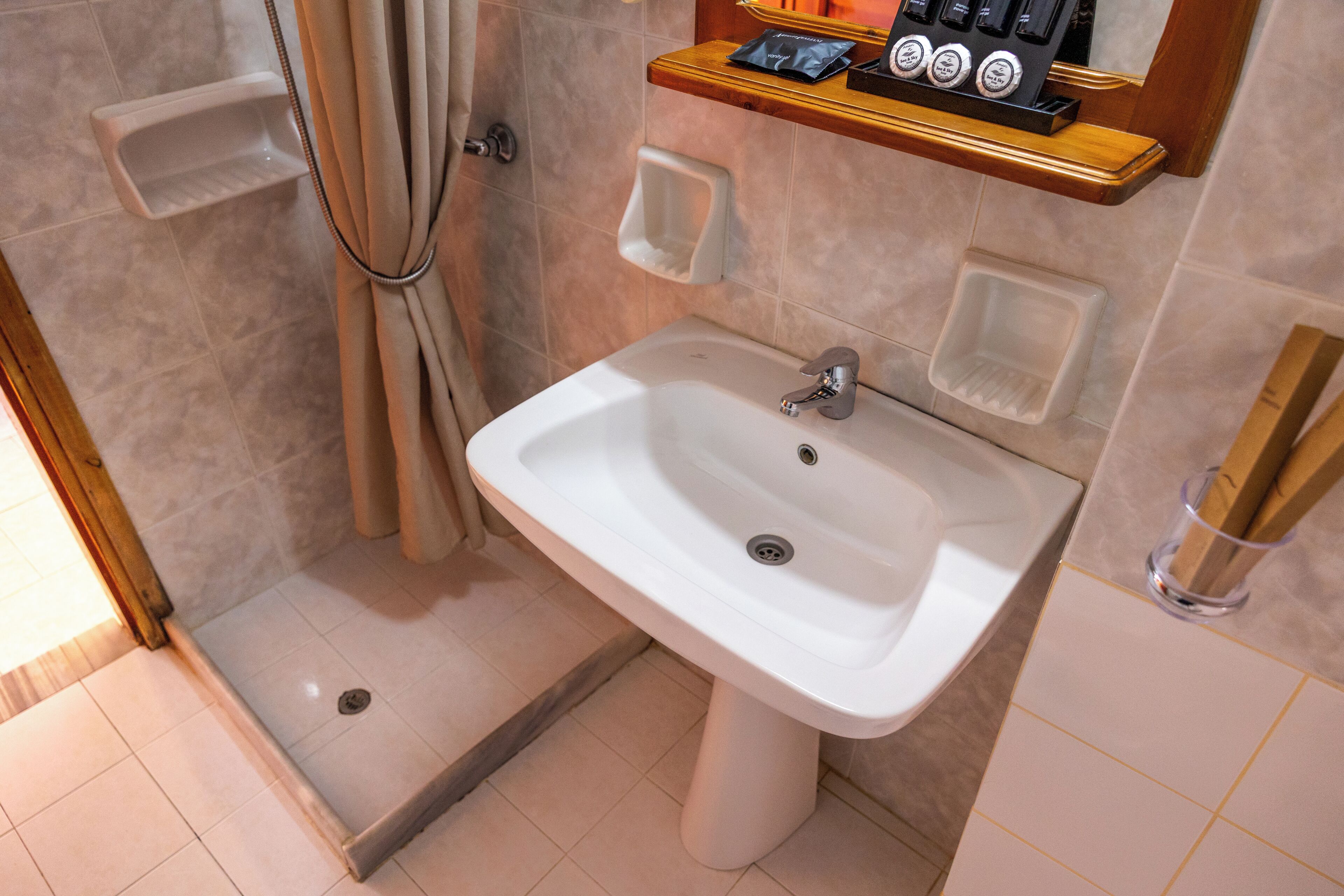 Un baño con lavamanos, ducha y estantes para guardar objetos.
