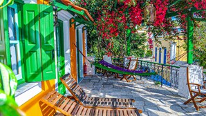 A courtyard with wooden benches, a hammock, and a railing. - Symi Garden Studios (Symi)