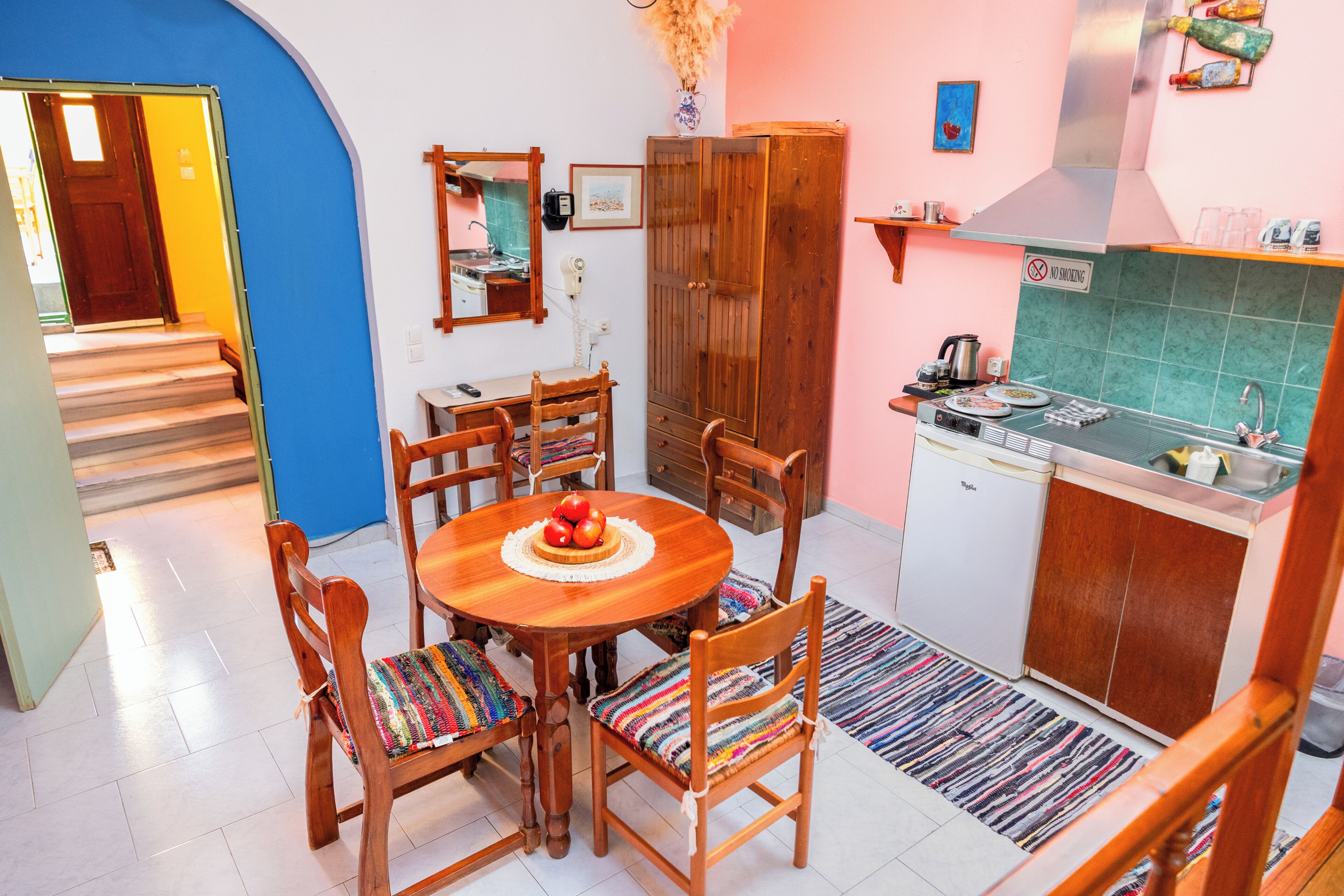 A compact kitchen with a dining table, chairs, a refrigerator, and a stove.