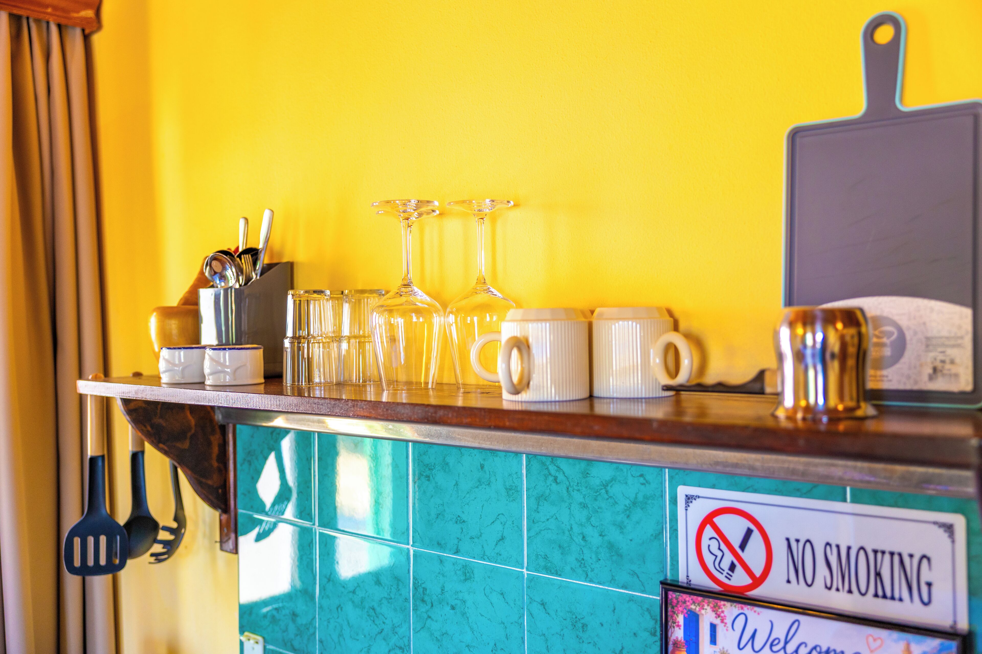 A kitchen counter with utensils, glasses, and a 'No Smoking' sign.