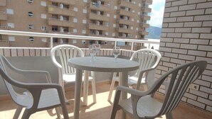 Un balcón con una mesa redonda y cuatro sillas, con vista a un edificio residencial.
