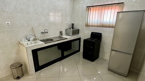 A modern kitchen with a stainless steel sink, a microwave, a stove, and a refrigerator. - Hotel Fátima  (Tete)