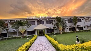 A hotel entrance with a paved pathway, yellow hedges, and a modern building with air conditioning units. - Hotel Fátima  (Tete)