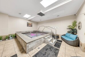 A spa area with a hot tub, steps, a sofa, and potted plants. - Plantation Dunes Condos (Gulf Shores)