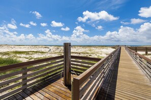 A wooden boardwalk leading to a beach with sand dunes and a clear blue sky. - Plantation Dunes Condos (Gulf Shores)