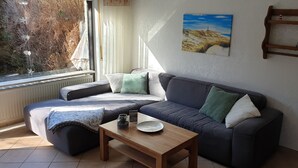 A cozy living room with a dark-colored sofa, a wooden coffee table, and a painting on the wall.