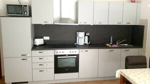 A compact kitchen with a microwave, coffee maker, and oven.