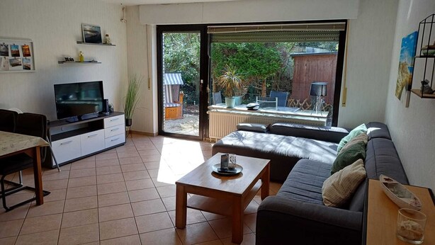 A living room with a sofa, a coffee table, a TV, and a dining area.