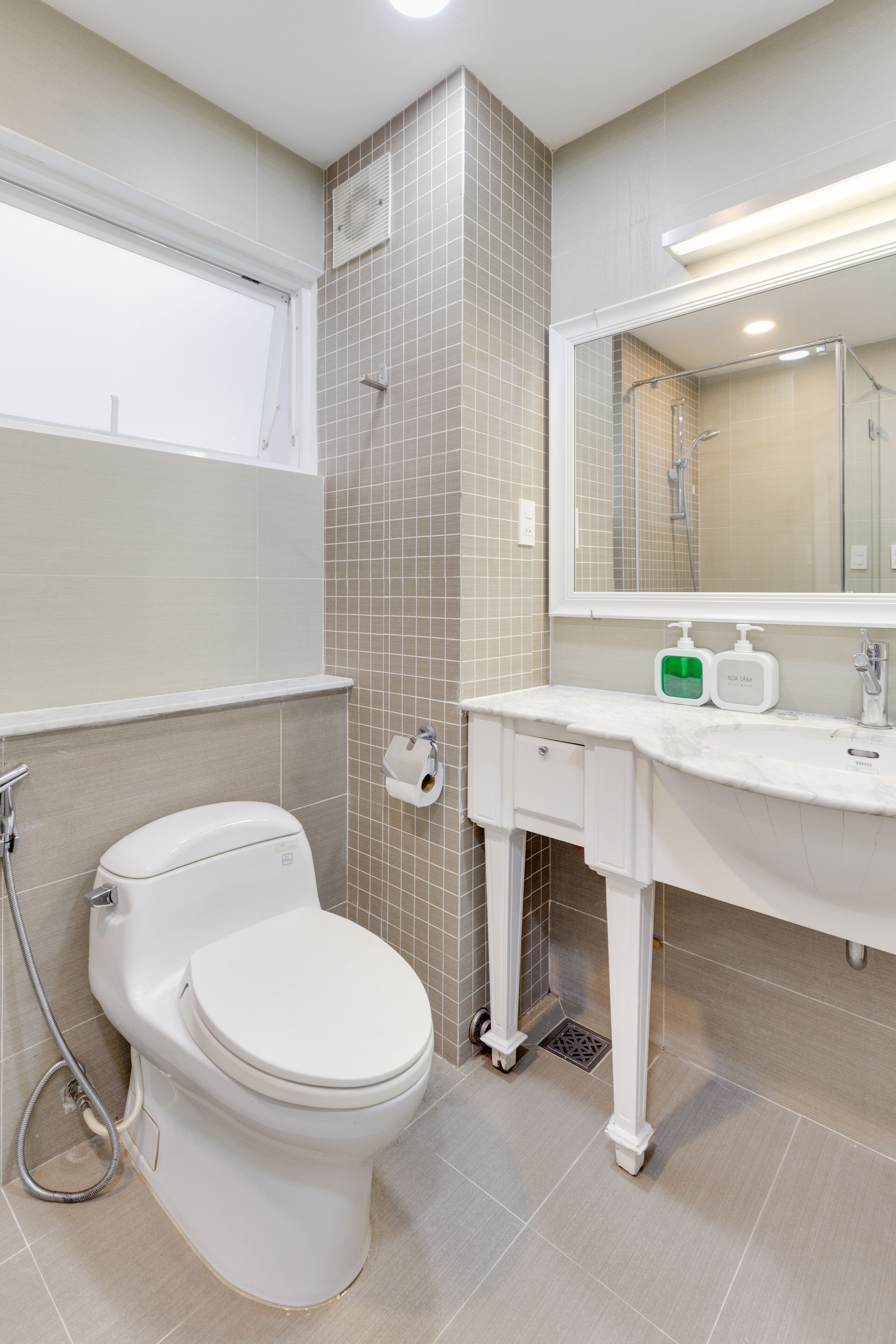 A modern bathroom with a toilet, sink, and mirror.