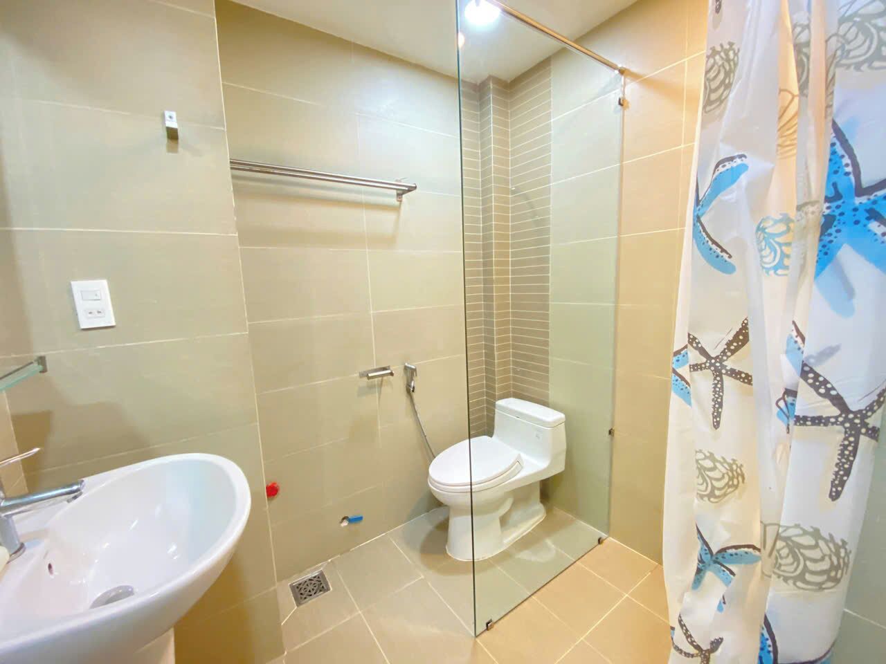 A bathroom with a glass shower enclosure, a toilet, and a sink.