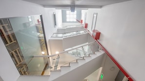 A multi-level interior with glass railings and a red handrail, featuring a modern architectural design. - Saigon Authentic Hostel & Tours (Ho Chi Minh City)