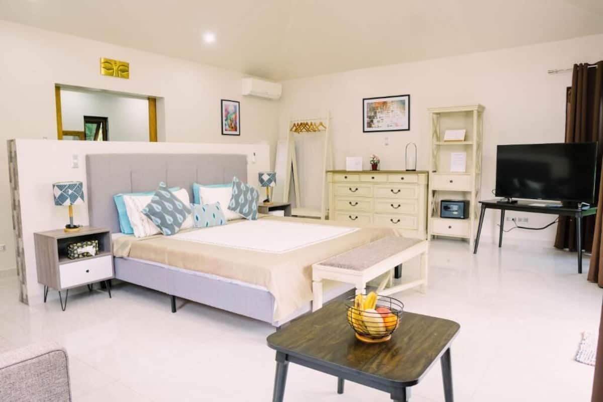 A modern bedroom with a large bed, bedside tables, a TV, and a desk.