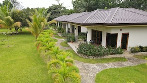 A row of white buildings with tiled roofs, surrounded by well-maintained gardens and palm trees. - Denika's Suites (Puerto Princesa)