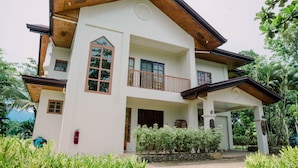 A two-story building with a balcony, large windows, and a stone pathway leading to the entrance. - Denika's Suites (Puerto Princesa)
