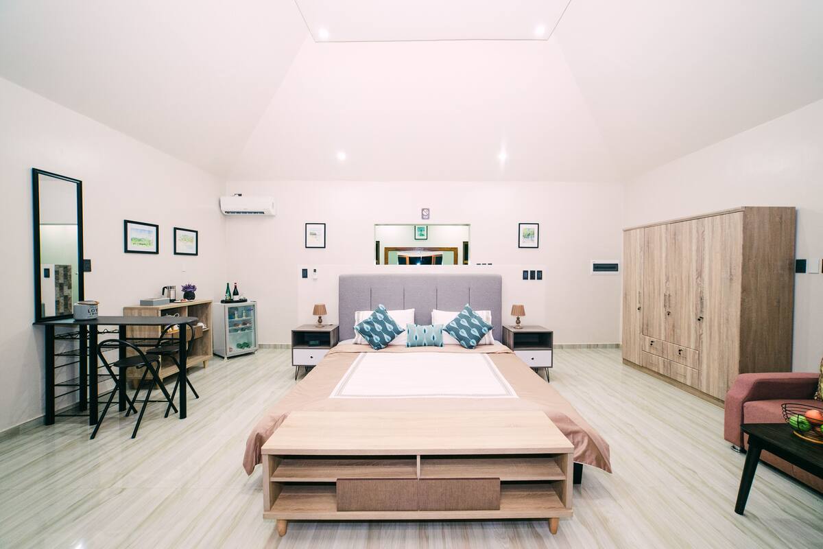 A spacious bedroom with a large bed, a desk, and a wardrobe.